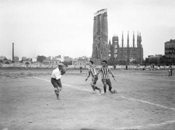 Partit de futbol amistós entre el Barcelona i l’Europa al camp de l’Europa, amb el temple de la Sagrada Família al fons, 1917. Fons i autoria: Frederic Juandó Alegret. (CAT AGDB R.55548)