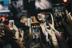 Fotografia: nombroses mans sostenen a l'aire un telèfon mòbil per captar un esdeveniment