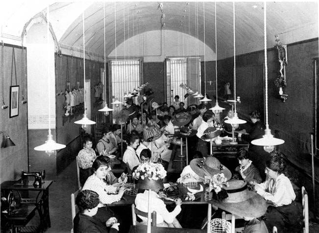 Classe de confecció de capells. Mercè Carbonell asseguda al fons, c. 1910. Autoria desconeguda. Fons: Diputació de Barcelona. (CAT AGDB R.3189)